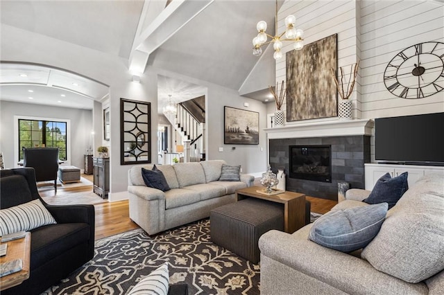 living room with a fireplace, high vaulted ceiling, hardwood / wood-style flooring, and a notable chandelier