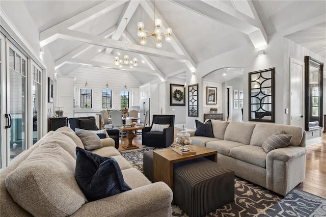 living room featuring an inviting chandelier, hardwood / wood-style flooring, beam ceiling, and high vaulted ceiling