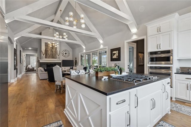 kitchen with beamed ceiling, light hardwood / wood-style flooring, stainless steel gas cooktop, a chandelier, and white cabinets