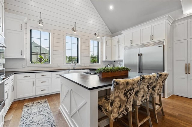 kitchen featuring built in fridge, a healthy amount of sunlight, light hardwood / wood-style flooring, and a center island