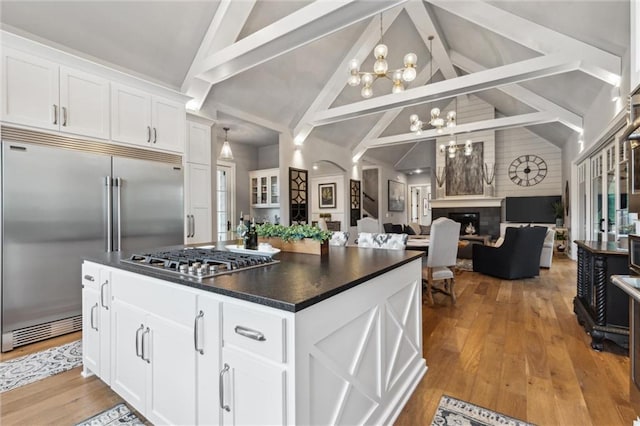 kitchen with beamed ceiling, stainless steel appliances, a chandelier, light wood-type flooring, and white cabinets