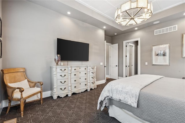 carpeted bedroom with a tray ceiling and an inviting chandelier