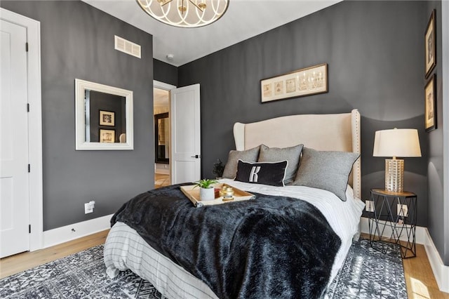 bedroom with an inviting chandelier and light hardwood / wood-style floors