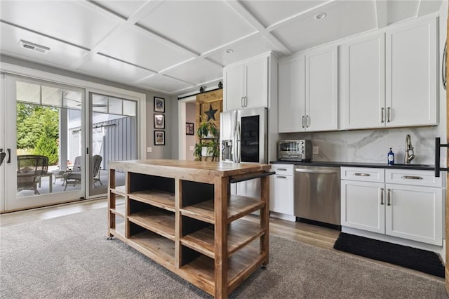 kitchen with coffered ceiling, tasteful backsplash, stainless steel appliances, white cabinetry, and light wood-type flooring