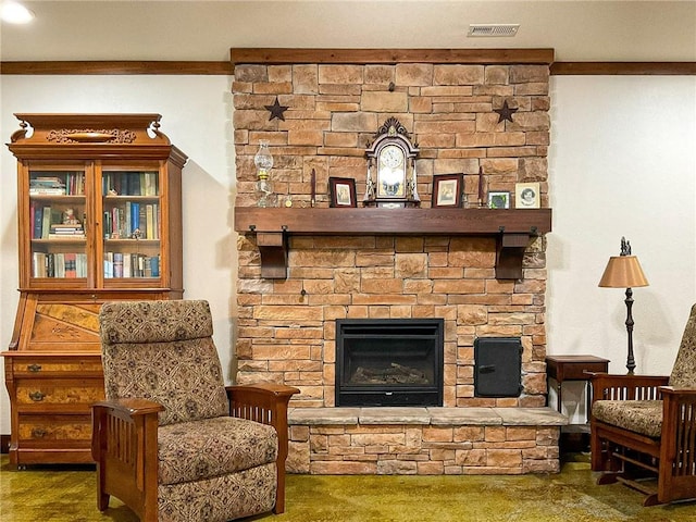 living area with a stone fireplace, dark carpet, and ornamental molding