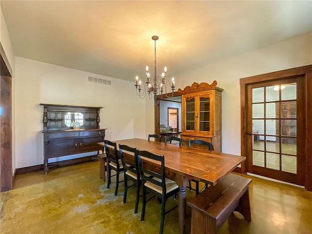 dining area featuring concrete flooring and a notable chandelier