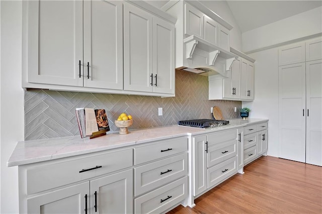 14500 Meadow Ln, Leawood, KS 66224 - kitchen with tasteful backsplash, light stone counters, stainless steel gas stovetop, and white cabinetry
