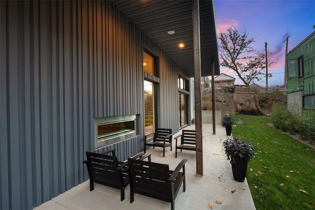 patio terrace at dusk featuring a lawn