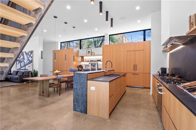 kitchen with sink, a wealth of natural light, a kitchen island with sink, and pendant lighting