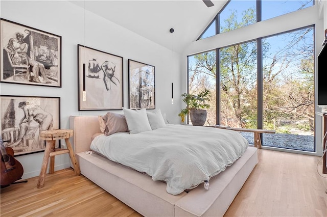 bedroom featuring high vaulted ceiling and light hardwood / wood-style floors