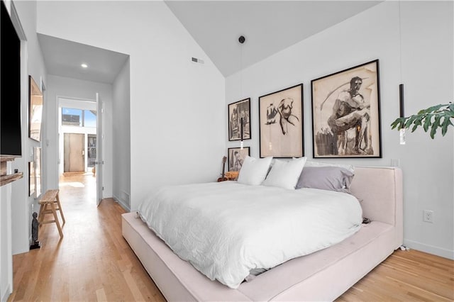 bedroom with high vaulted ceiling and light hardwood / wood-style floors