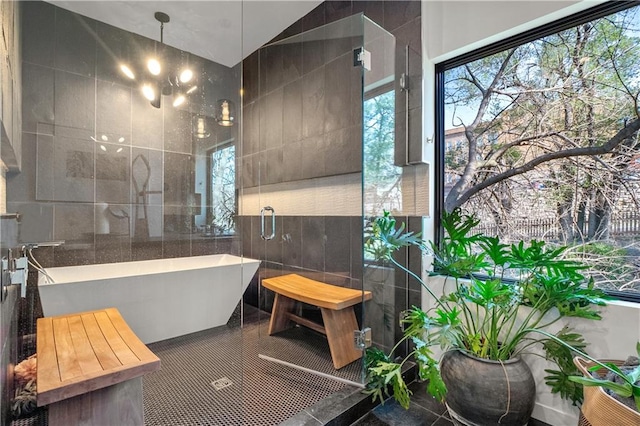 bathroom featuring an inviting chandelier, tile walls, tile floors, and a washtub