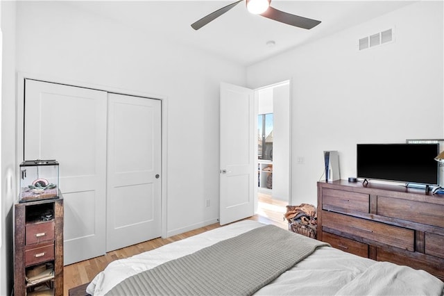 bedroom with a closet, light hardwood / wood-style floors, and ceiling fan