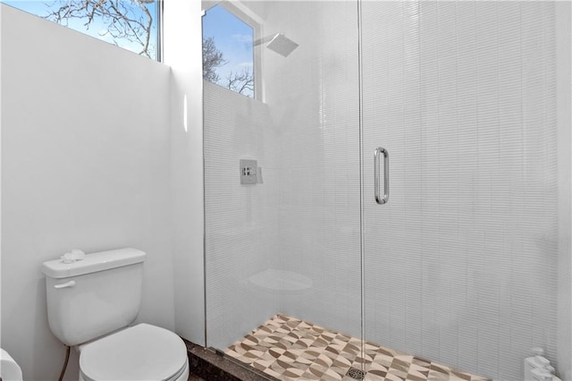 bathroom with toilet and a shower with door