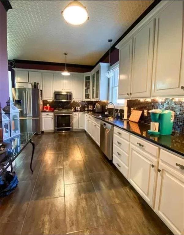 kitchen featuring white cabinetry, hanging light fixtures, appliances with stainless steel finishes, and tasteful backsplash