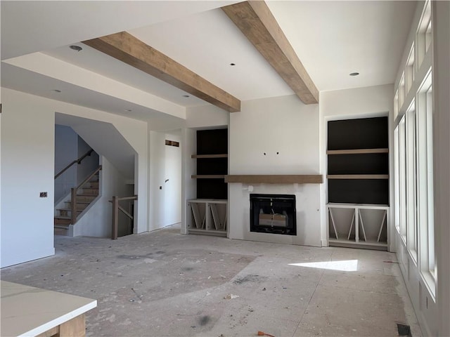 unfurnished living room featuring beam ceiling and a healthy amount of sunlight