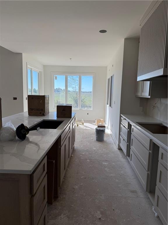 kitchen featuring dark brown cabinets, light stone counters, sink, and tasteful backsplash