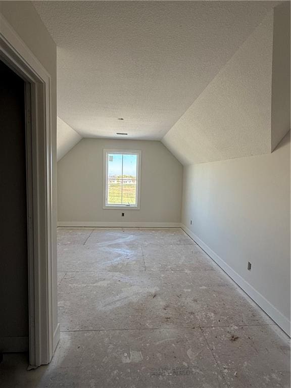 additional living space with a textured ceiling and vaulted ceiling