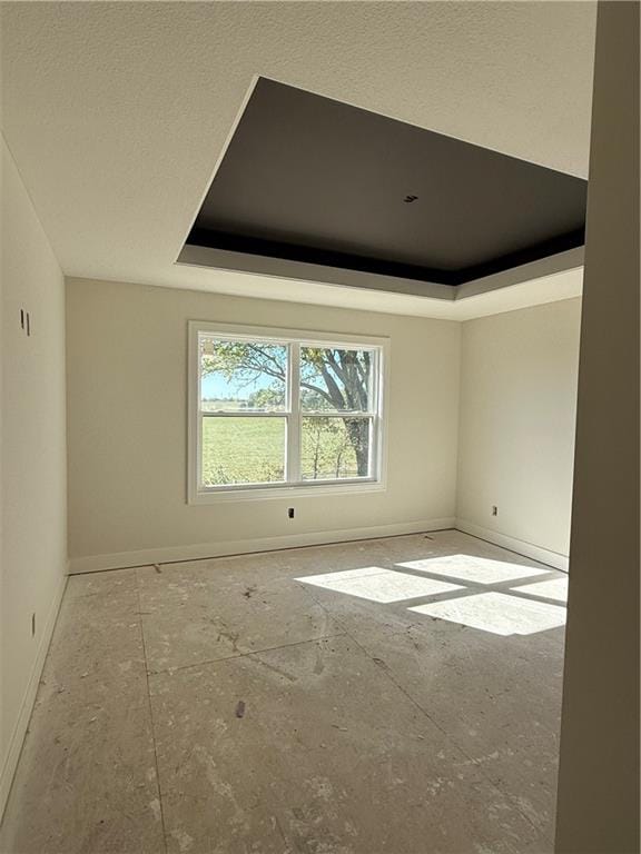 unfurnished room featuring a tray ceiling and a textured ceiling