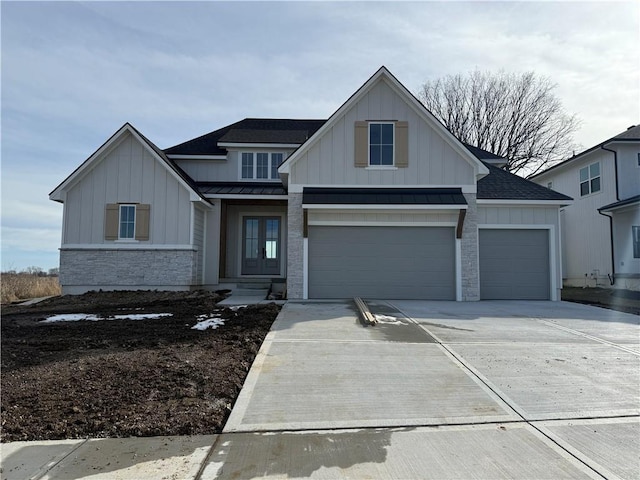 view of front facade featuring driveway, stone siding, metal roof, a standing seam roof, and board and batten siding