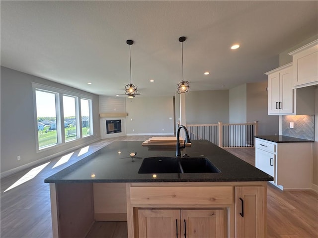 kitchen featuring sink, white cabinetry, decorative light fixtures, a center island with sink, and dark hardwood / wood-style floors