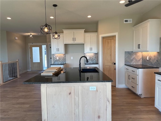 kitchen featuring white cabinetry, a kitchen island with sink, sink, and light hardwood / wood-style flooring