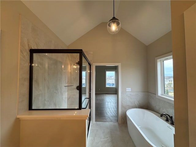 bathroom featuring vaulted ceiling, plenty of natural light, tile walls, and separate shower and tub