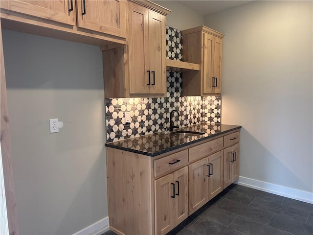 kitchen featuring tasteful backsplash, sink, dark stone countertops, and light brown cabinetry