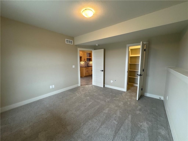 unfurnished bedroom with a spacious closet, dark carpet, and a closet