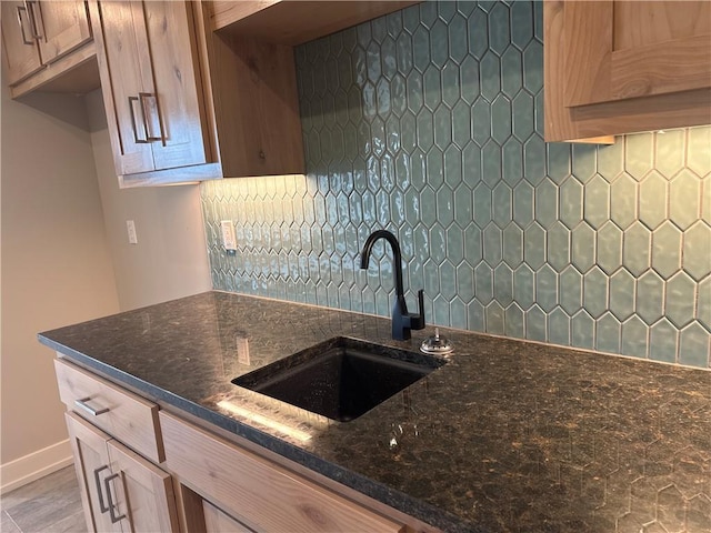 kitchen featuring tasteful backsplash, dark stone counters, and sink