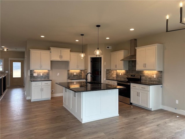 kitchen with wall chimney exhaust hood, stainless steel electric range oven, a kitchen island with sink, and white cabinets