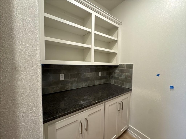 kitchen with backsplash, dark stone counters, and white cabinets