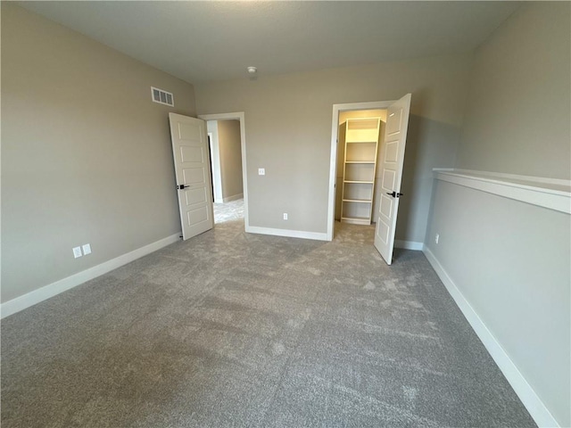 unfurnished bedroom featuring a closet, a spacious closet, and carpet flooring