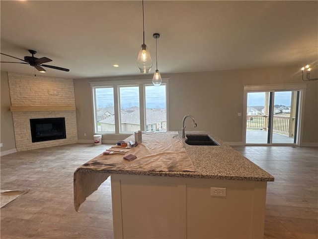 kitchen featuring sink, decorative light fixtures, a large fireplace, a mountain view, and an island with sink