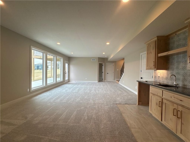 unfurnished living room featuring sink and light carpet