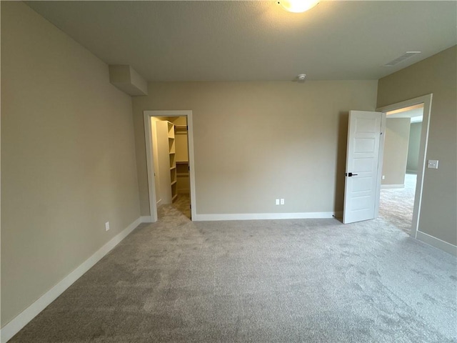 unfurnished bedroom featuring a walk in closet, light colored carpet, and a closet