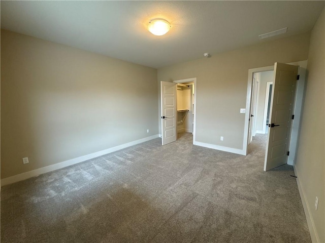 unfurnished bedroom with a spacious closet, a closet, and carpet