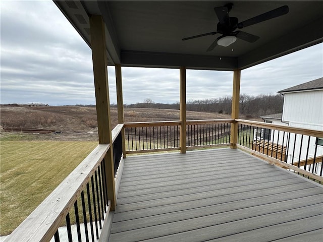 deck with a rural view, a lawn, and ceiling fan