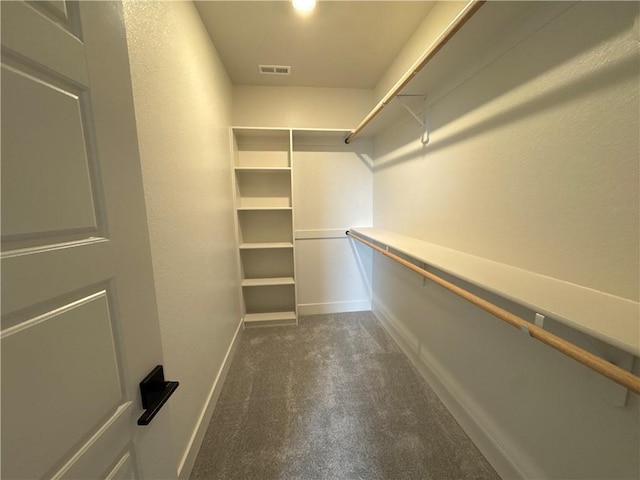 walk in closet with dark carpet