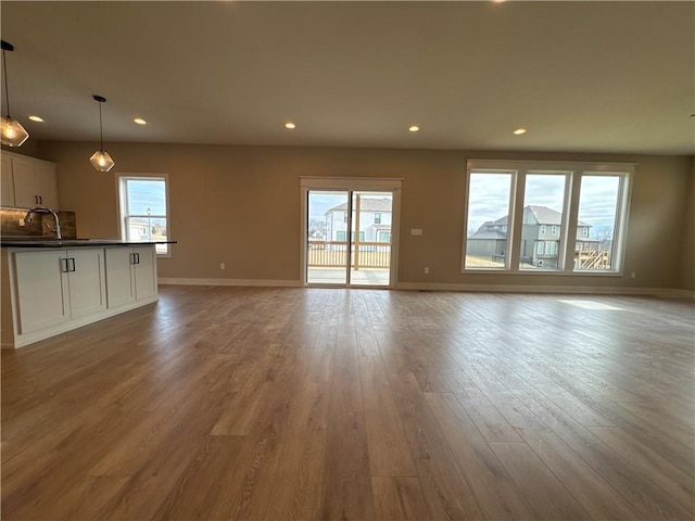 unfurnished living room with plenty of natural light, sink, and light hardwood / wood-style floors