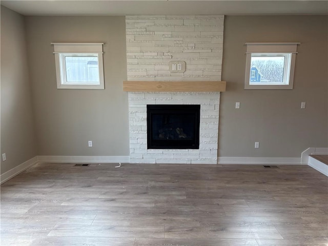 unfurnished living room with a large fireplace and light wood-type flooring