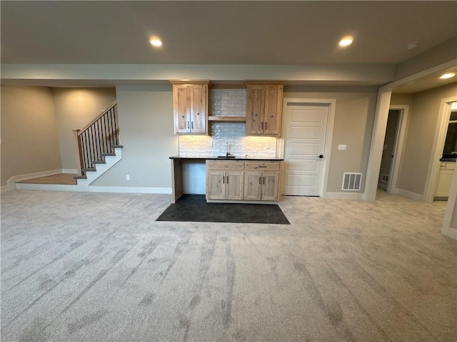 kitchen featuring light carpet, tasteful backsplash, and light brown cabinets