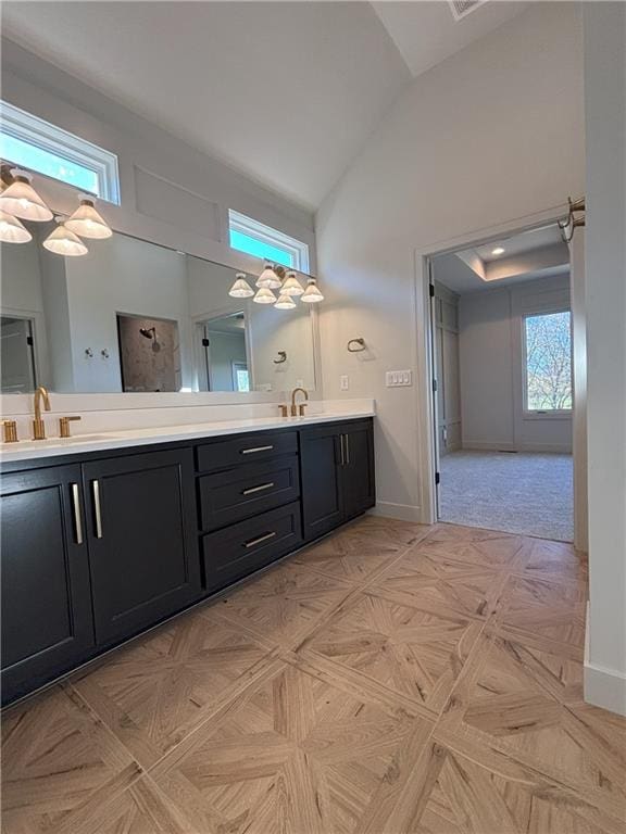 bathroom with a wealth of natural light, vanity, high vaulted ceiling, and parquet flooring