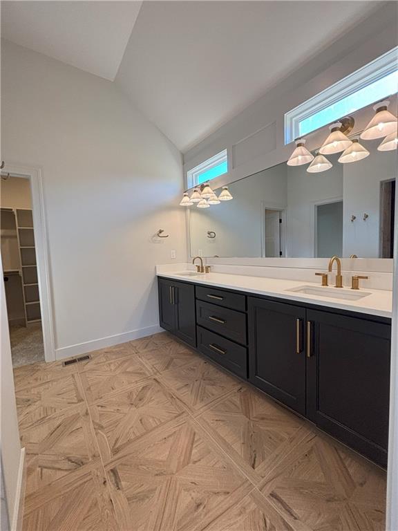 bathroom with high vaulted ceiling, vanity, and parquet floors