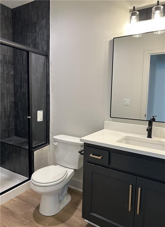 bathroom with toilet, vanity, hardwood / wood-style floors, and a shower with shower door