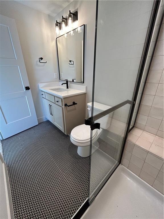 bathroom featuring toilet, vanity, and a shower with shower door