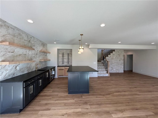 kitchen featuring sink, a breakfast bar, pendant lighting, a kitchen island, and light wood-type flooring