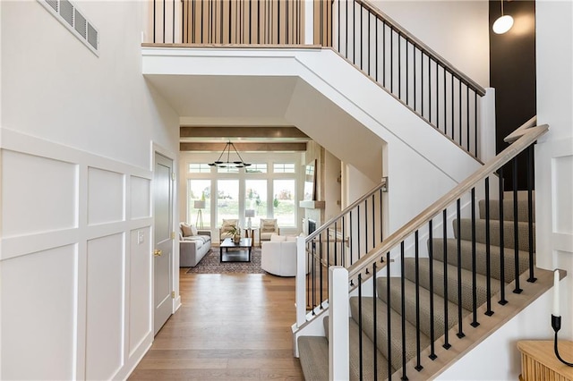 stairs featuring hardwood / wood-style floors, a notable chandelier, and a towering ceiling