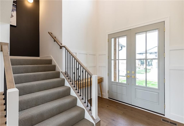 foyer entrance with french doors, a wealth of natural light, and hardwood / wood-style floors