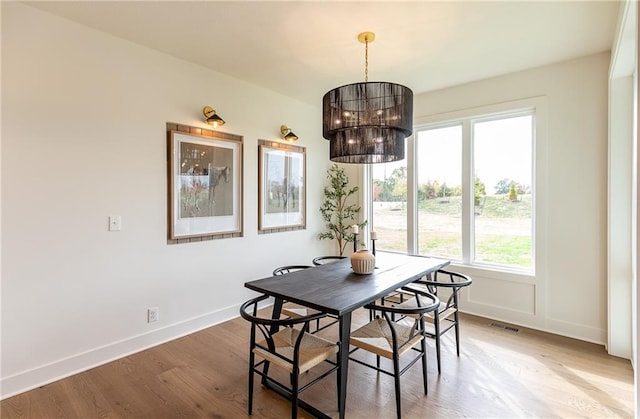 dining area featuring hardwood / wood-style flooring and an inviting chandelier